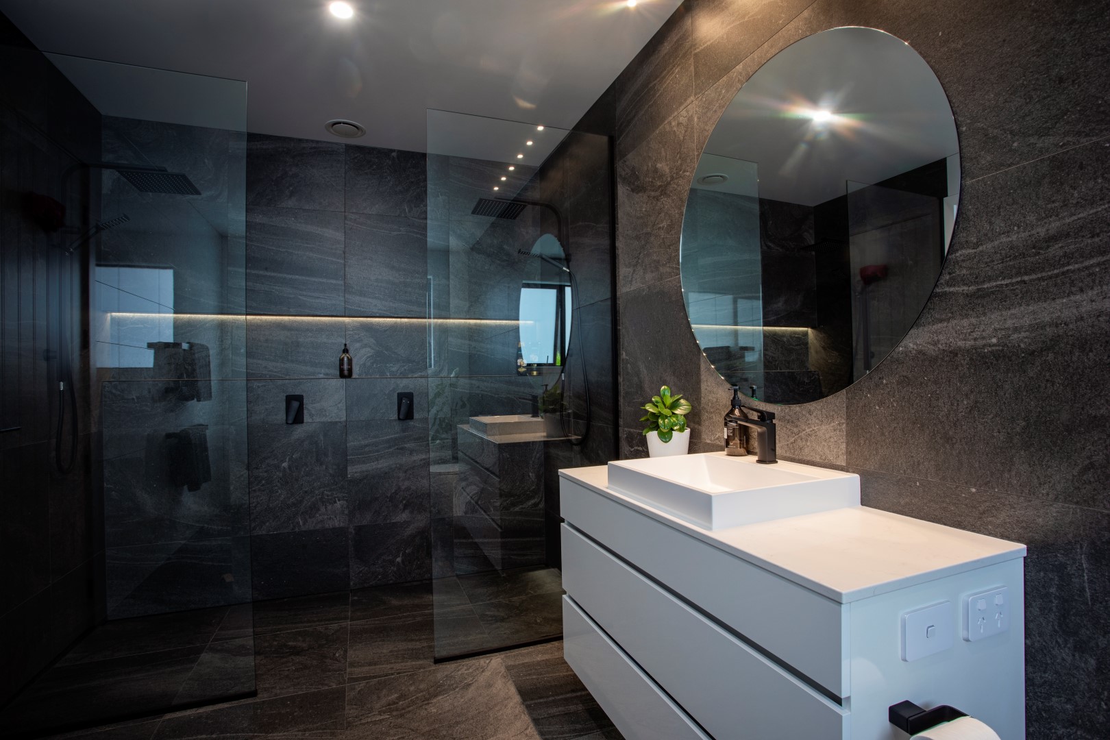 dark-bathroom-design-charcoal-tiles-white-vanity-round-mirror-shower-recess-arcline-architecture