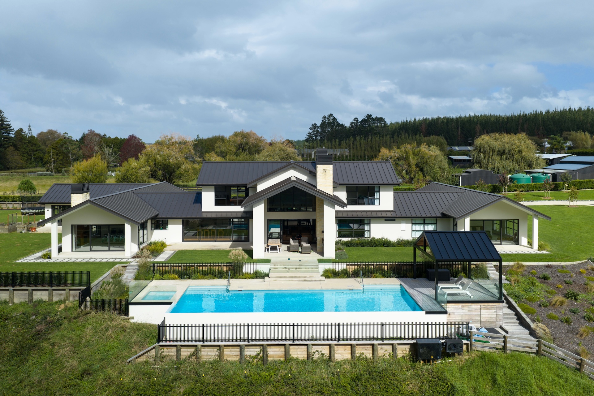 arcline-architecture-drone-shot-of-modern-home-with-pool-spa-and-rural-northland-backdrop