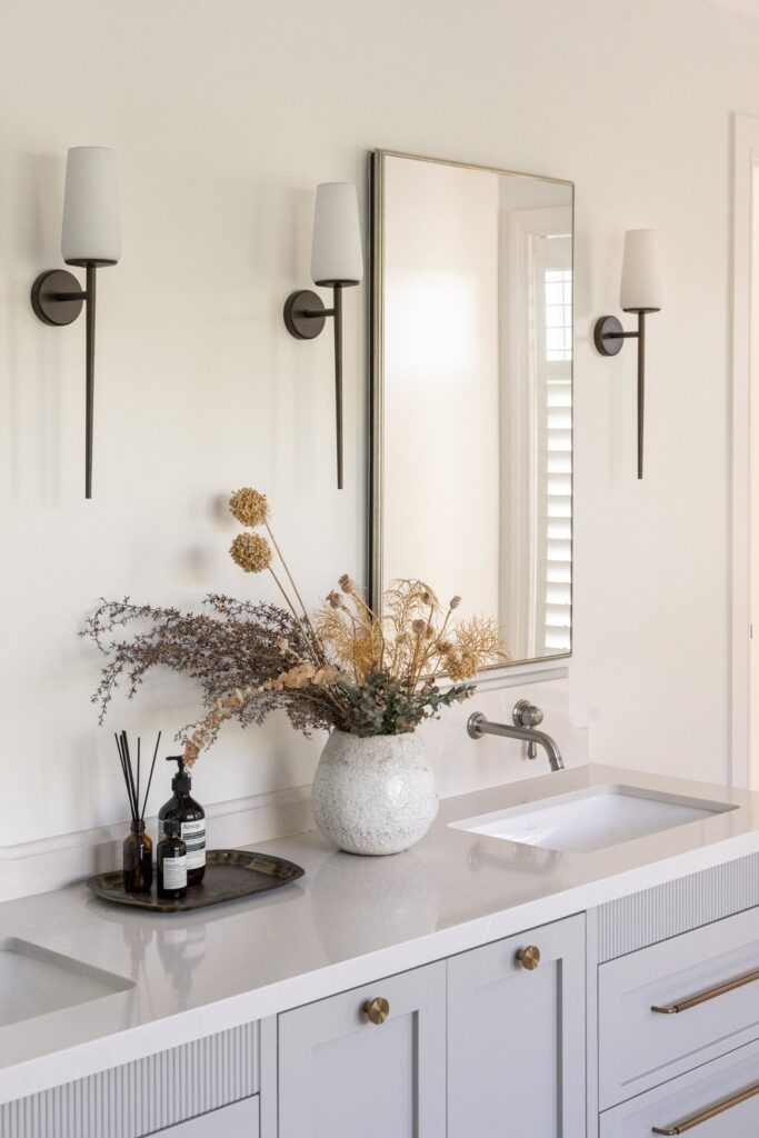 bathroom-vanity-detail-with-wall-sconces-and-dried-flowers-arcline-architecture