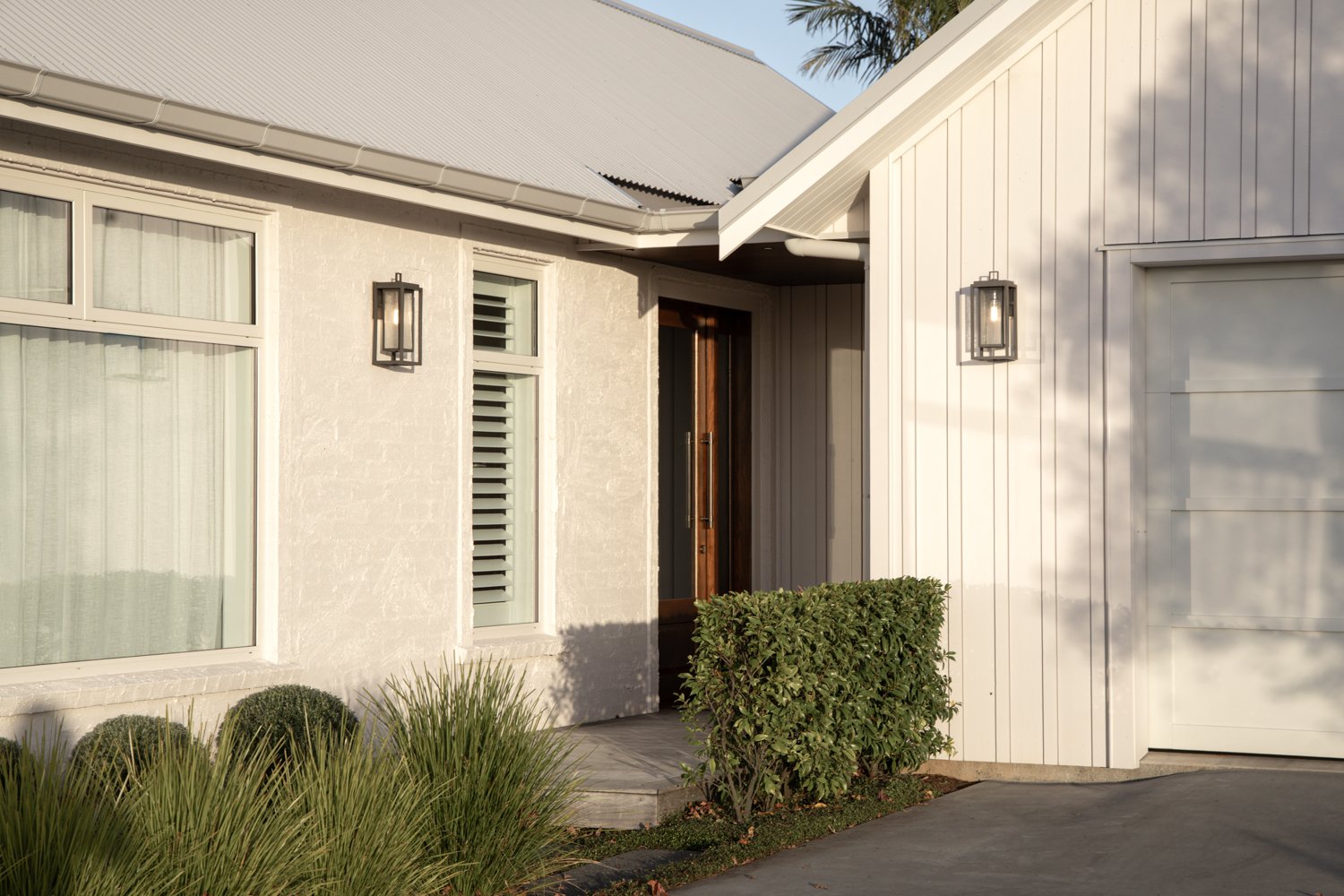 front-entry-with-timber-door-and-wall-lanterns-at-dusk-arcline-architecture